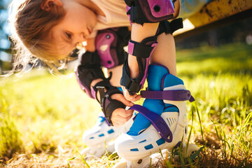 Little girl dresses roller skates while sitting on the bench. Active healthy lifestyle. safe riding