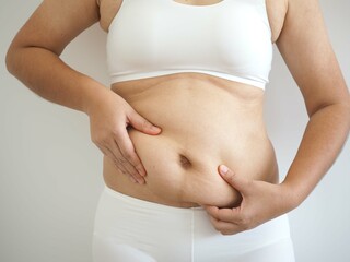 Fat woman, obese woman hand holding excessive belly fat. concept to reduce belly and form healthy abdominal muscles. closeup photo, blurred.