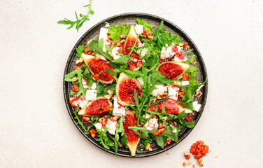 Fresh summer fig salad with white cheese, nuts, arugula and jam dressing on white table background, top view, copy space