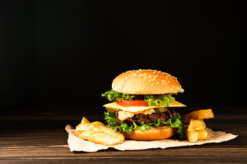 Homemade beef burgers and french fries on dark background.
