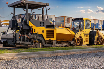 Obraz na płótnie Canvas Asphalt paving equipment. Asphalt paver and heavy vibratory roller. Construction of new roads and road junctions. Heavy construction industrial machinery.