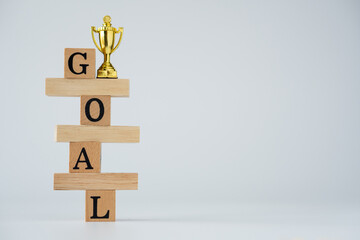 gold cup on wood block. word goal build be wooden blocks on white background.goal Business concept