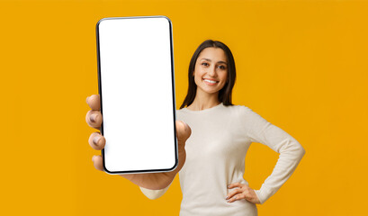 Mobile app mockup. Happy woman showing big cellphone with white blank screen, lady demonstrating...