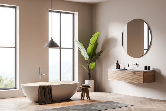 Light bathroom interior with sink and bathtub, decoration on deck and window