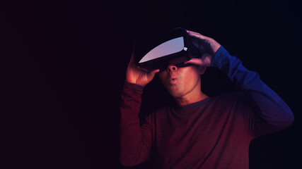 Man wearing virtual reality Headset on neon color background. VR, future, technology online concept. Glasses of virtual reality and exploring the metaverse. Technology, gaming, entertainment concept.