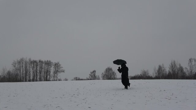 Plaque doctor in black bird beak mask with umbrella goes from the hill.   Image of all pandemics