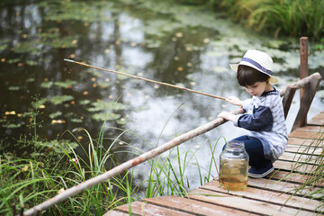 A child is fishing in the autumn morning. Autumn sunset on the pond. A fisherman with a fishing rod on the walkway.