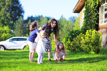 Obraz premium Young large family on a summer morning walk. Beautiful mother with children is playing in the park.