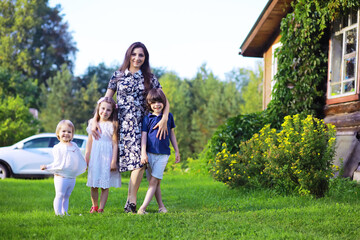 Obraz premium Young large family on a summer morning walk. Beautiful mother with children is playing in the park.