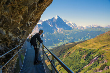 Fototapeta na wymiar Mountaineer at Cliff walk, Grindelwald First, stunning view to Bernese Alps