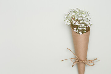 Flower arrangement - white flowers in craft packaging on a textured background.