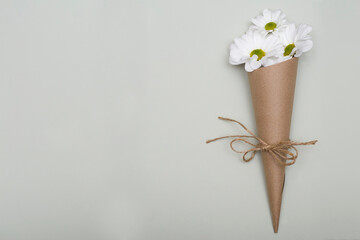 Flower arrangement - white flowers in craft packaging on a textured background.