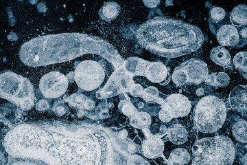 Ice texture with air bubbles background. The textured cold frosty surface of the ice on dark...