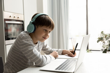 Smiling teen gen Z schoolkid in wireless headphones studying at home, watching learning webinar, online class, virtual lesson, listening to audio tutorials on laptop, consulting teacher on video call