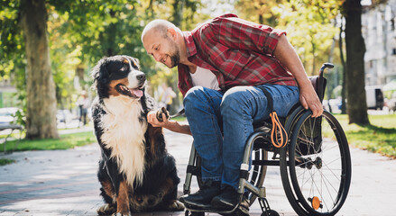 Happy young man with a physical disability who uses wheelchair with his dog. - obrazy, fototapety, plakaty