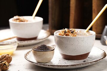 Traditional east european (ukrainian, polish, belarusian) religious christmas dish kutia made of wheat, poppy seeds, honey, walnuts and dried berries. modern style in porcelain bowls, wooden plates