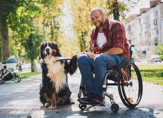 Happy young man with a physical disability who uses wheelchair with his dog. - obrazy, fototapety, plakaty