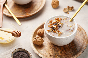 Traditional east european (ukrainian, polish, belarusian) religious christmas dish kutia made of wheat, poppy seeds, honey, walnuts and dried berries. modern style in porcelain bowls, wooden plates