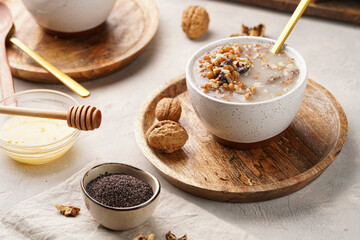 Traditional east european (ukrainian, polish, belarusian) religious christmas dish kutia made of wheat, poppy seeds, honey, walnuts and dried berries. modern style in porcelain bowls, wooden plates