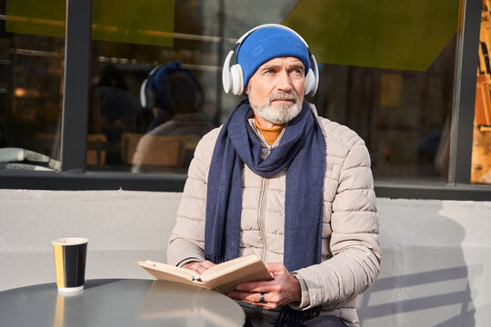 Senior man wearing headphones enjoying of his favorite book