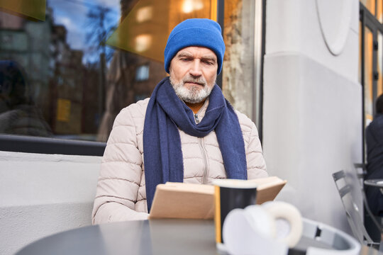 Handsome old gentleman enjoying novel at outdoor cafe