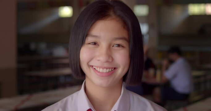 Slow motion scene of a young Asian teenage high school student girl is smiling happily.