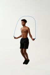 Fototapeta premium Black smiling sportsman jumping on skipping rope