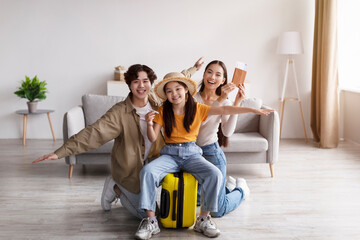 Happy teen girl in hat hold plane sitting on suitcase, young asian lady and man rejoice, have fun...