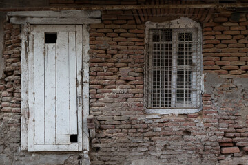 Fototapeta na wymiar Vintage old wooden door and white window in an old red brick stone wall.