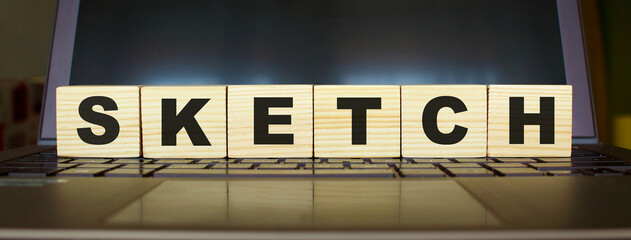 Obraz premium Word SKETCH. Wooden cubes with letters isolated on a laptop keyboard. Business Concept.