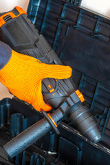 Hands in protective gloves, hammer drill, perforator, case, tool box