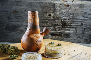 Old brown steamung bong and open cannabis grinder with chopped marijuana weed and medical cannabis...