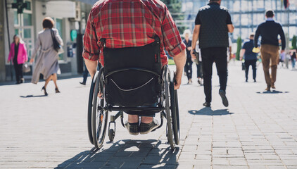 Young man with a physical disability who uses wheelchair walk at the street