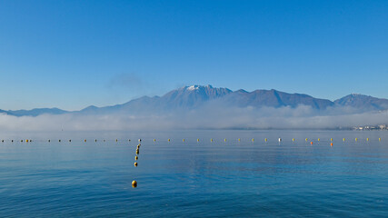 Paesaggio del lago di giorno, con cielo azzurro e nebbia bassa sopra l'acqua