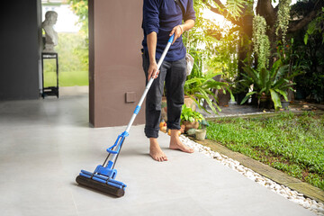 Male janitor with mop cleaning modern house floor