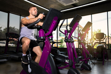 Attractive man working out on an exercise bike in gym.