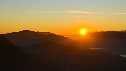 Sole che tramonta sopra il lago, bellissimo momento nel mese di ottobre, con scia dorata sopra le montagne