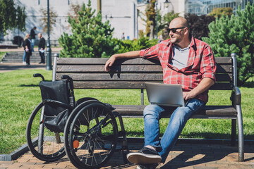 Fototapeta premium Freelancer with a physical disability who uses wheelchair working at the park