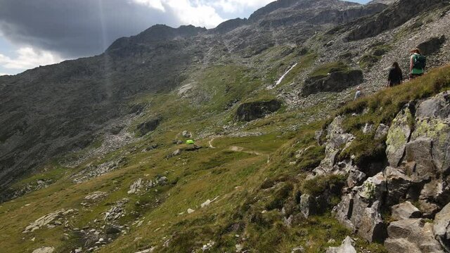 People enyoing life outdoors and walking on a narrow hiking train in the mounatins. 4k drone video. Zillertal, Austria