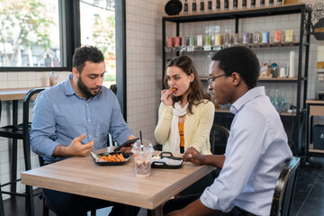Group of business people sitting at the coffee shop or cafe and eating nugget and sausage. Manager looking at smartphone. Brake after long meeting. Business and relaxation concept