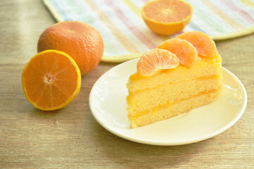 Fototapeta na wymiar orange cake with cream topping fruit in plate on table