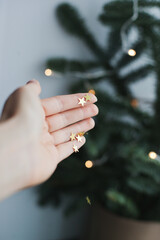 Golden glitter stars on a palm of a hand near christmas tree as festive background