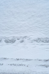 Background with dirty snow, top view. The surface of a winter field partially stained with mud.