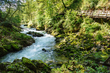 Vintgar Gorge in Slovenia near Lake Bled. Wild nature with river and waterfall in deep canyon. Accessible for tourists on bridges and footbridges.