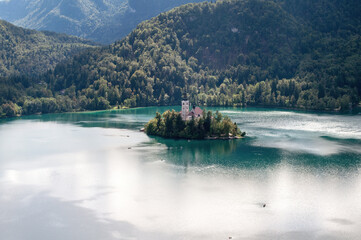 An island with a church with a tall tower in the middle of Lake Bled in Slovenia.