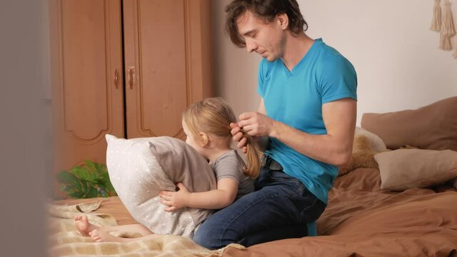 Dad and daughter play in bedroom, happy family on bed. Home interior, lifestyle, real life, funny video. They love each other, satisfied with life. man doing tail to child
