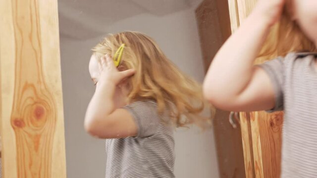 little sweet girl flaunts herself near mirror, poses, examines herself, squirms. Child model. Funny