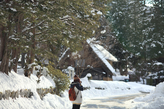 A girl shooting a picture at Shiragawa go village in winter season was covered with snow around town, Japan  