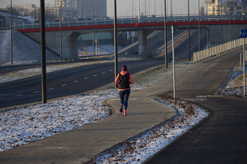 Person running on the street during the winter. Morning jogging in the city.