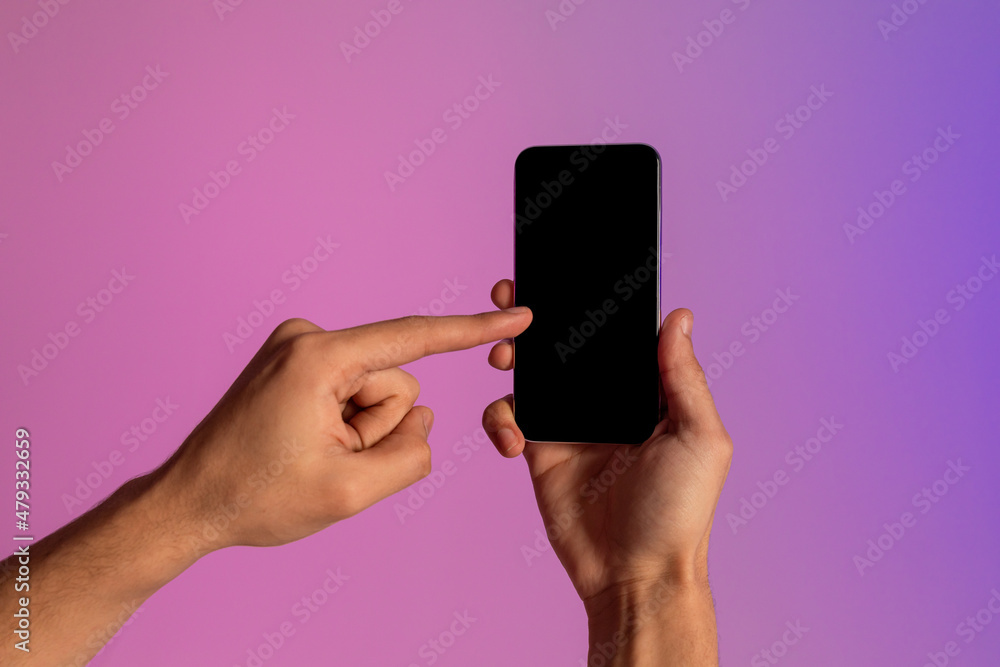 Poster Unrecognizable millennial guy using smartphone with blank screen in neon light, offering mockup for mobile app